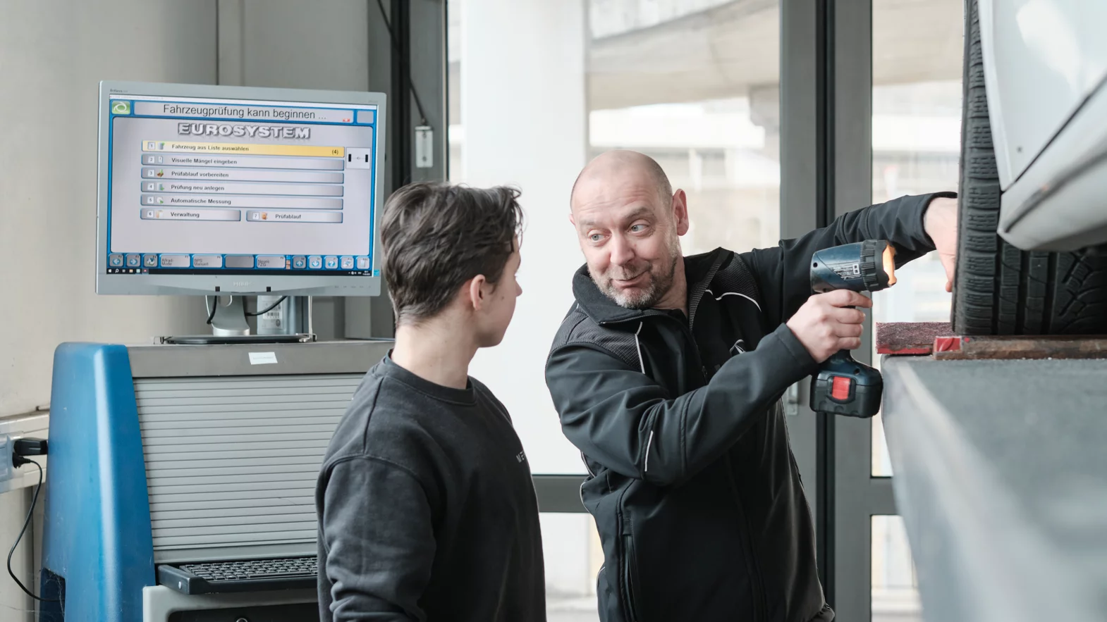 Automobil-Mechatroniker:in EFZ Fachrichtung Nutzfahrzeuge mit dem Berufsbildenden während der Arbeit.